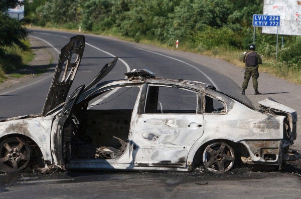 An interior ministry serviceman stands next to a burnt car following a shoot-out in Mukacheve, Ukraine, July 11, 2015. Ukraine's President Petro Poroshenko has instructed law enforcement agencies to disarm and detain those who staged the shoot-out in the town of Mukacheve, Zakarpattia region, which left several people wounded and some reportedly killed, local media reported. REUTERS/Stringer