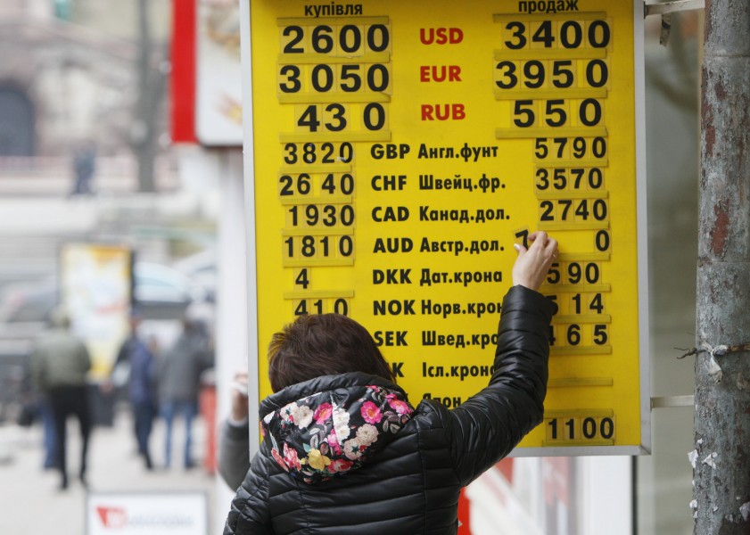 A woman changes an exchange rate on a display board at a currency exchange office in Kiev February 26, 2015. Ukraine's central bank unexpectedly banned most currency trading on Wednesday, only to abruptly reverse the decision overnight, causing havoc in the market for the plunging hryvnia. A separatist war in the east of the country has made it difficult to stabilise an economy on the verge of bankruptcy, and the hryvnia currency has already lost more than half its value so far this year after halving during all of 2014. REUTERS/Valentyn Ogirenko (UKRAINE - Tags: BUSINESS)