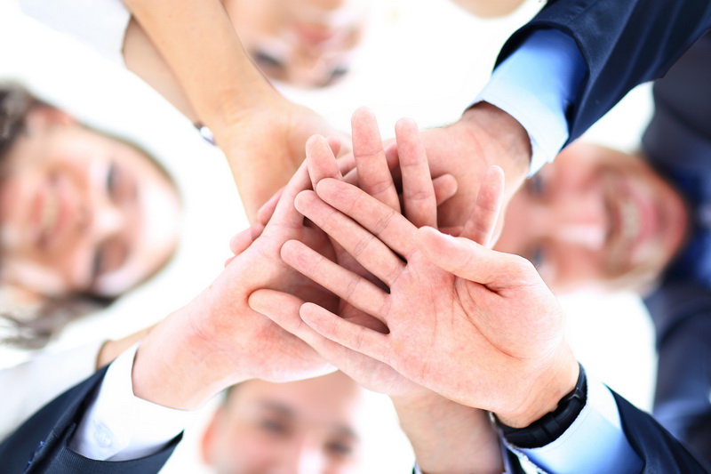 Small group of business people joining hands, low angle view